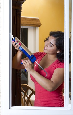 woman uses tool to plug energy leaks in her home