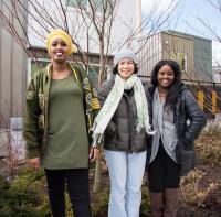 Image: three people stand outside a new housing development. Topic: Turning Crisis into Creation with Green Affordable Housing