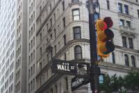 black street pole with street light and street sign saying "Wall St" against the backdrop of a tall, grey building with lots of windows, socially responsible investing must be a requirement