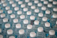 macro shot of rows of clear plastic water bottles with white caps. 