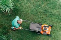 man pushing an orange lawnmower
