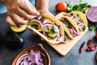 A taco filled with mushrooms, avocado, red onion, and cilantro. 