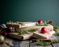 Gifts wrapped in brown paper with pine and ornaments around them. Sustainable gifts holidays.