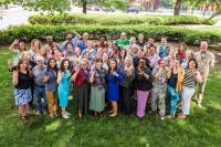 three rows of green america staff making the hand sign for I Love You in ASL