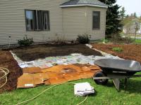 lawn being transformed into a climate victory garden with layers of cardboard and newspaper