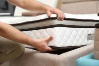 two hands lifting and placing a mattress on a bedframe