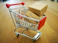 Image: tiny model shopping cart with Amazon boxes. Topic: Amazon Worker Rights: Issues At Home And Abroad