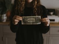 Image: person holding dollar bill. Topic: socially responsible finance