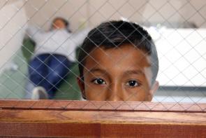 immigrant boy behind fenced glass