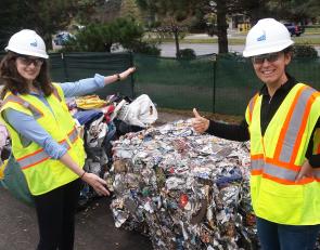Beth and Kristin stand in front of a bale of materials for recycling