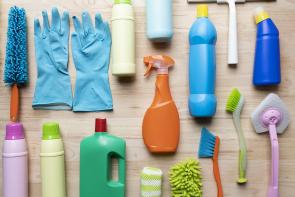Image: an array of cleaning products on a table. Topic: 13 Toxic Chemicals Lurking in Your Home