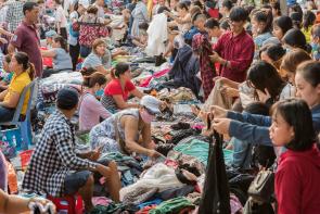 Image: people shop through secondhand clothes at Cho Con Market. Topic: When you donate clothes, they may not go where you think. Learn what really happens to your clothing castoffs.