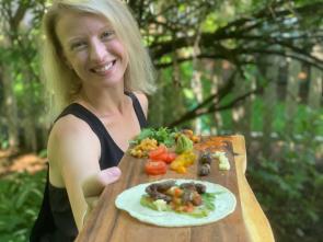 Dr. Cortni Borgerson serves up cicada tacos on a live edge wood cutting board.