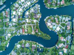 Drone image of a neighborhood in Fort Lauderdale, Florida. A winding river runs through the neighborhood. Homes have dock and boat access to the water.