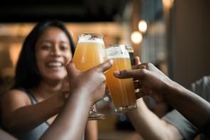 Friends toasting with craft beer glasses in a warm, social setting.