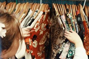 A woman browsing colorful clothes hanging on a rack. 