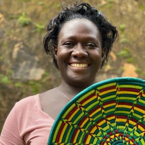 African basket weaver smiling and holding basket