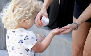 mom using moxe premium hand sanitizer on her child for clean hands
