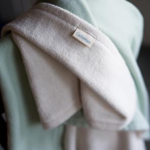 close up of toddler blanket draped beautifully over a chair. Blanket is mint green on one side and natural on the other. CastleWare Baby logo is facing the camera