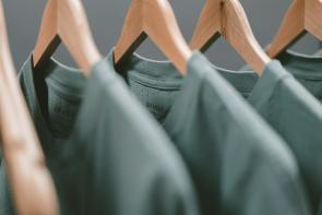 three green t-shirts on wooden hangers