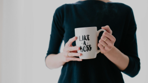 woman in black shirt holding white mug that reads Like A Boss