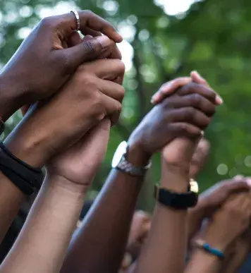 Image: hands held and thrust into the air. Topic: Green America's Work on Social Justice.