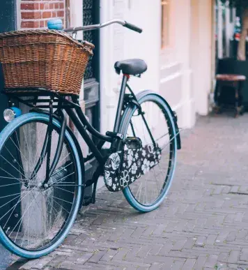 Image: bicycle with basket propped up against wall. Green living.