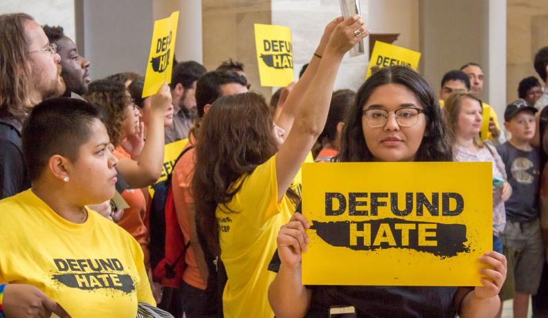 Protestor holds up sign that says "Defund Hate" at protest against ICE