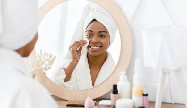 Black woman applying face products.