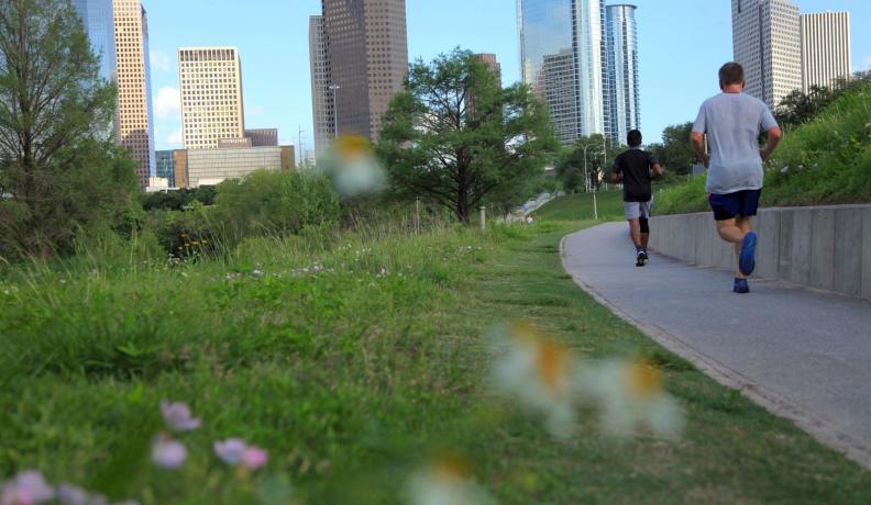Two people running in a green space at Buffalo Baou Park in Houston, Texas.