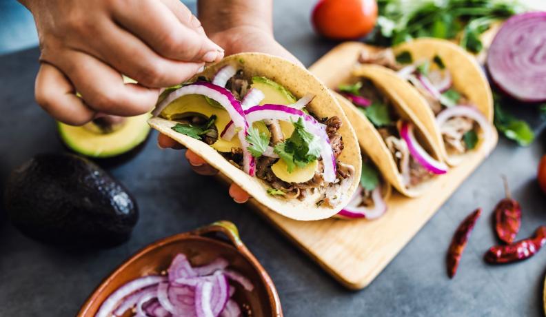 A taco filled with mushrooms, avocado, red onion, and cilantro. 