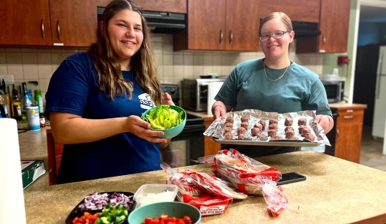 two college students showing what they're making for dinner. Baking meatballs and salad prepping.