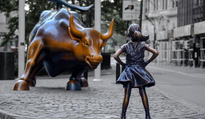 photo of the wall street bull facing a brass statue of a young girl standing proudly with her hands on her hips.