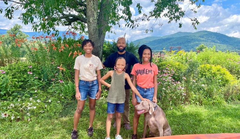 a family stands together with their dog smiling at the camera