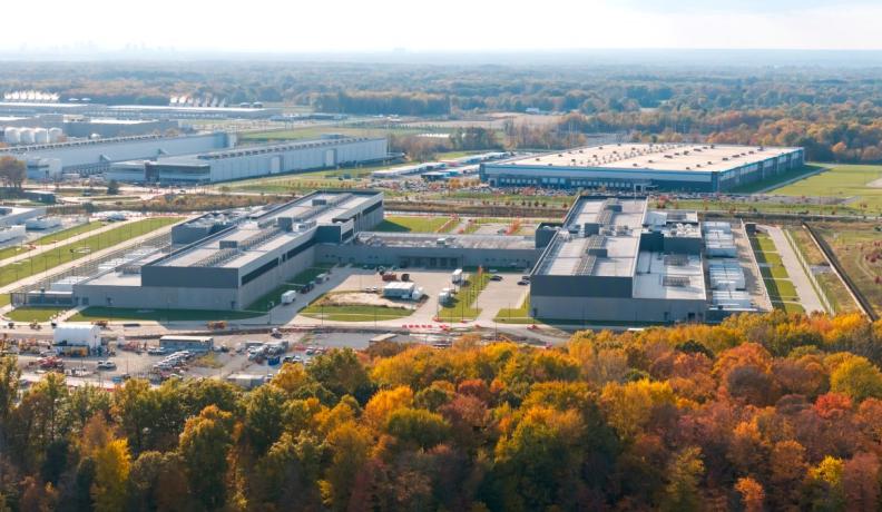 wide shot of a data center in Ohio from a hillside, so you can see the entire metropolis of warehouses. In the foreground are orange and yellow trees in the fall.