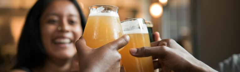 Friends toasting with craft beer glasses in a warm, social setting.