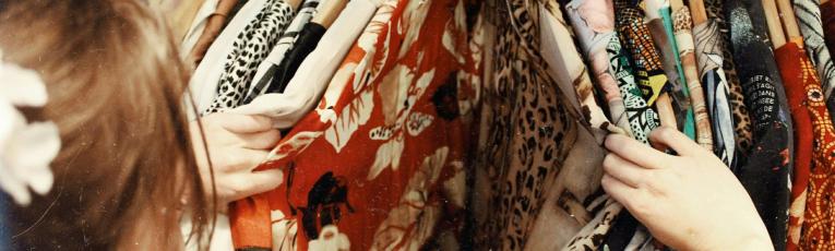 A woman browsing colorful clothes hanging on a rack. 
