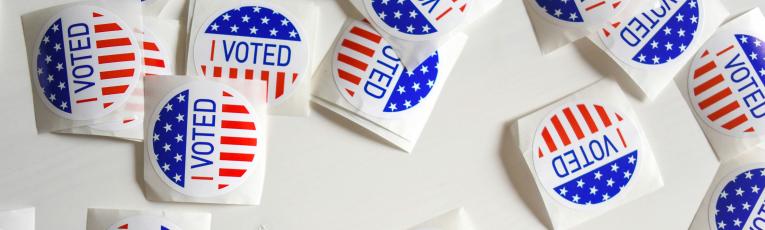 Stickers that read "I Voted" scattered across a white table top.