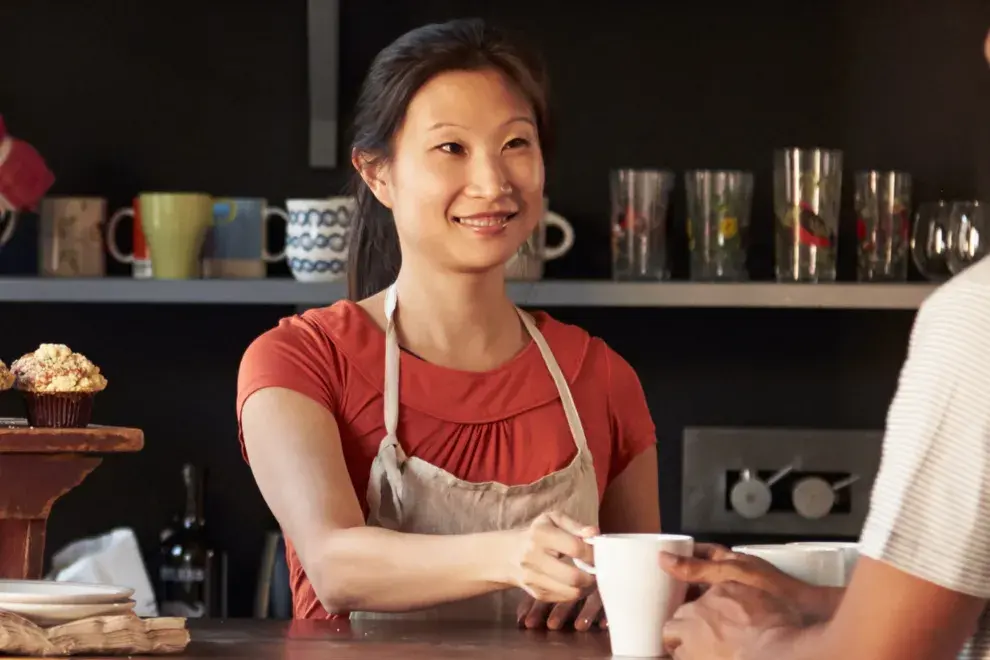 Image: Barista giving coffee to customer. Text: Find green products and services.