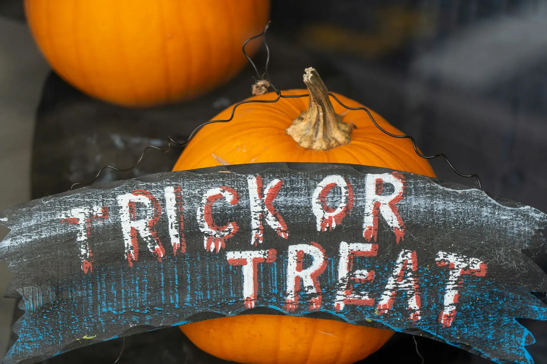 Trick or treat sign leaned on an orange pumpkin