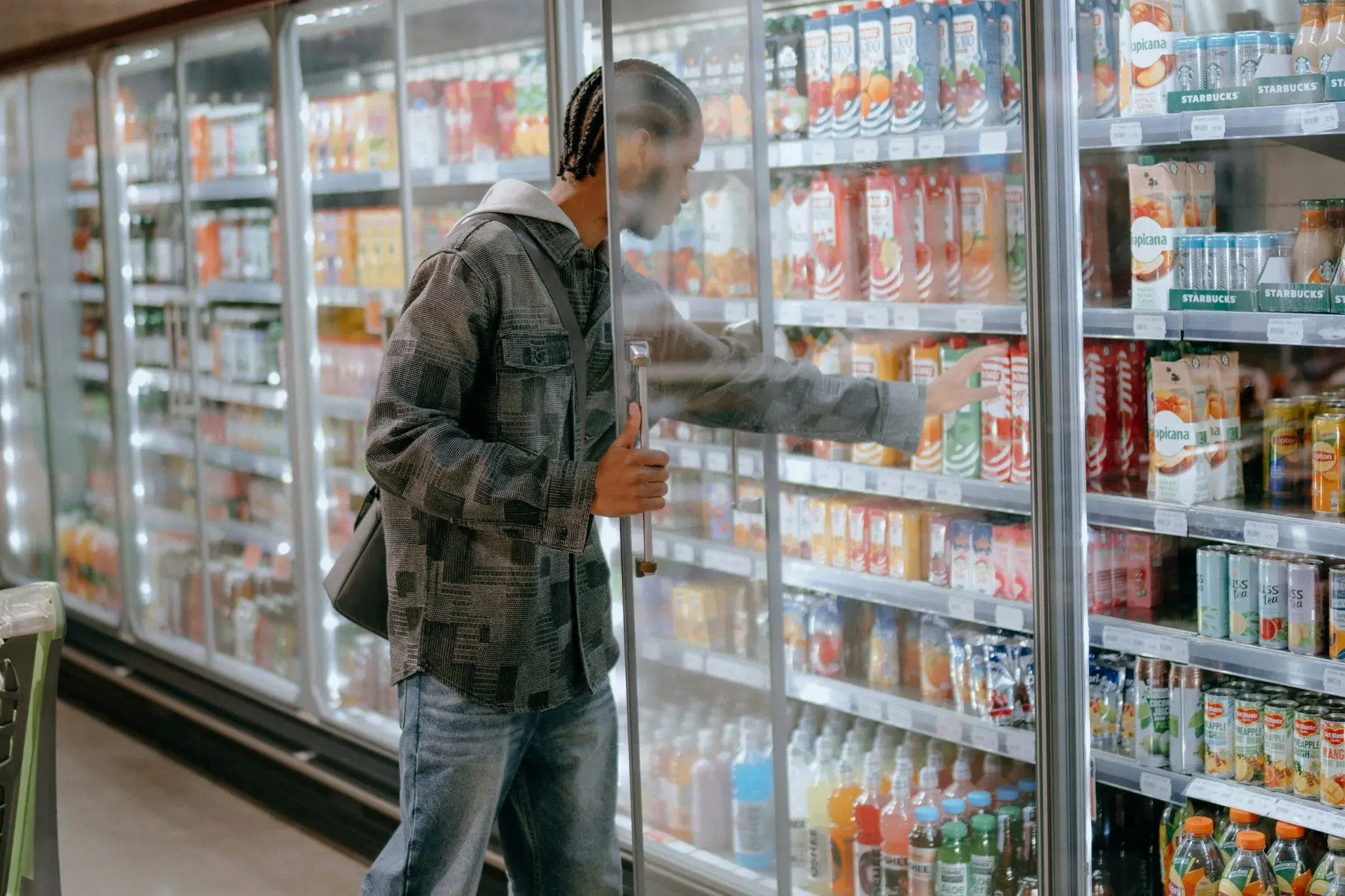 A young man shopping in the refrigerated aisle of a supermarket. 
