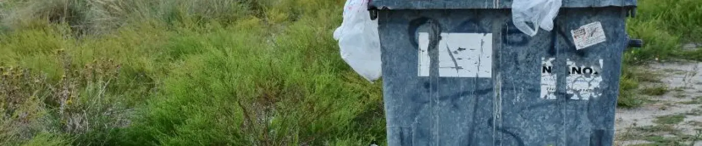 Bin filled with garbage in a field