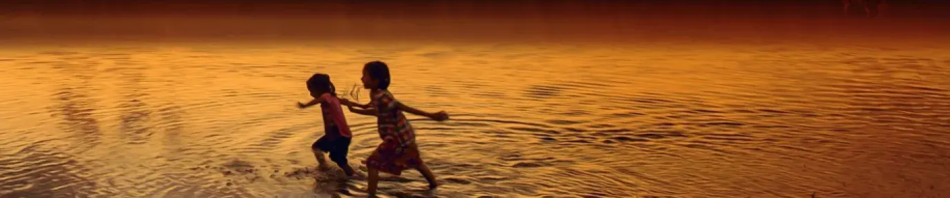 Image: children wading through a river, with a forest fire in the background. Title: The Tragedy in the Amazon: What We Can Do 