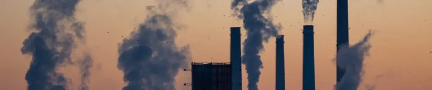 energy plants emitting clouds of pollution against sunset 