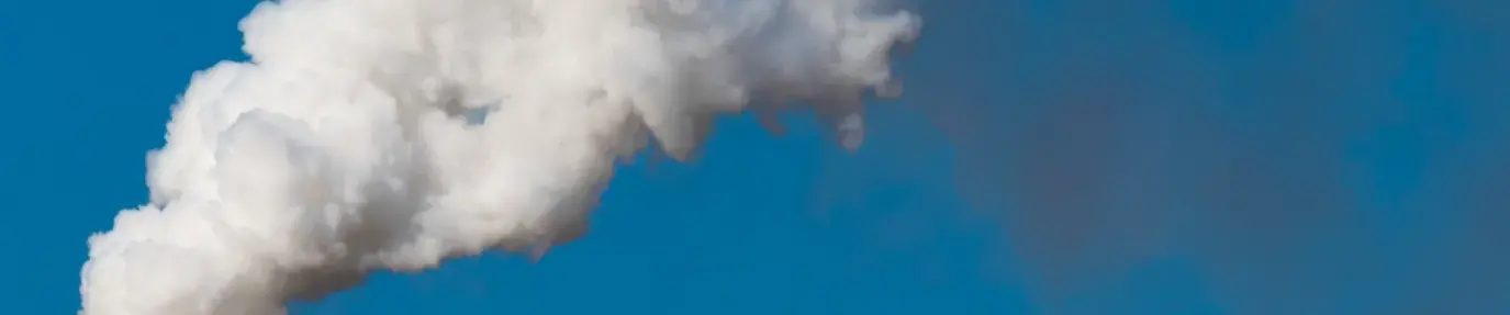 smoke billowing out of a factory chimney against a blue sky