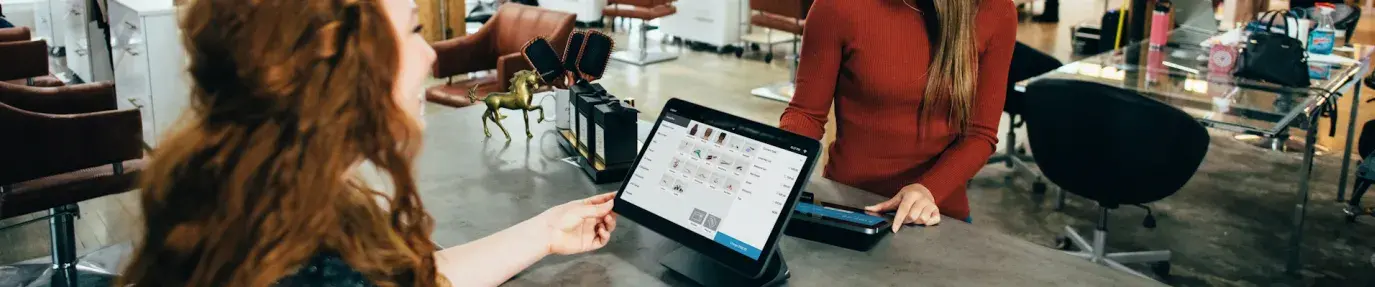 A small, industrial style store, a redheaded white woman checks out an Asian woman at the counter; the IRA has several new small business resources