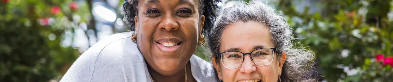 Dr. Lakeisha Thorpe, a Black woman, wears a light grey cardigan over a peach colored shirt. She stands next to Fran Teplitz, retiring co-executive director of Green America, a white woman with greying hair, glasses, in a burgundy floral top.