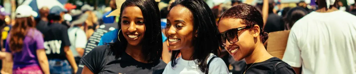 Three young Black women hold a sign that says Juneteenth at a public event