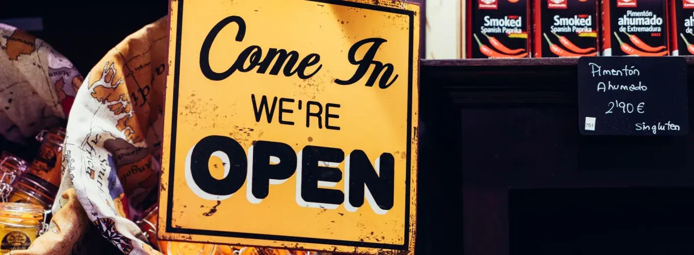 Image: orange sign stating "Come in, we're open." Topic: Free Store: Where Everything Is, Yes, Free