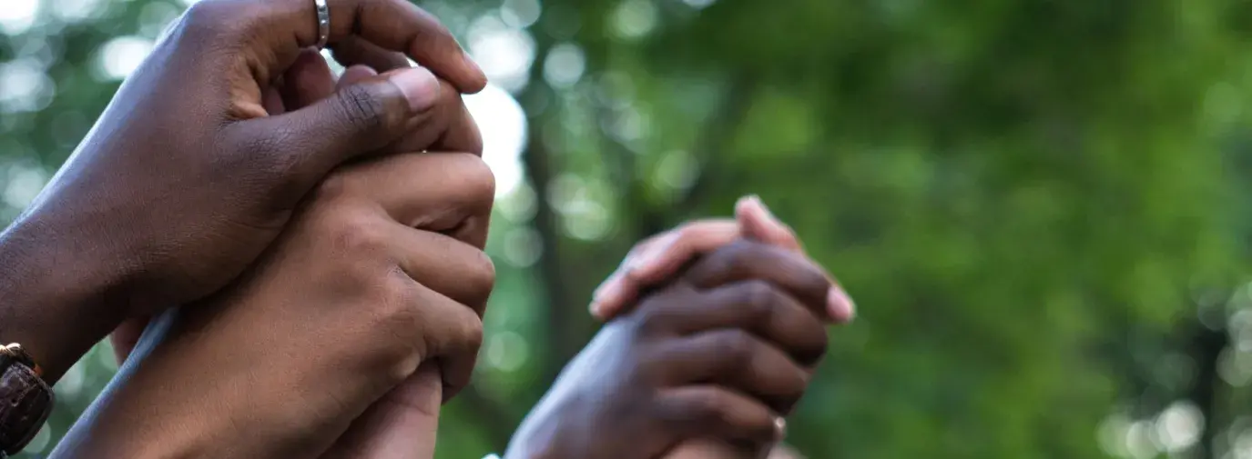 Image: hands held and thrust into the air. Topic: Green America's Work on Social Justice.